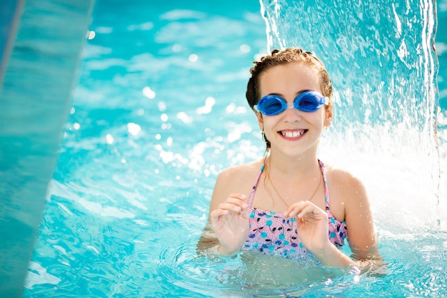 The girl bathes in the pool in blue goggles for swimming