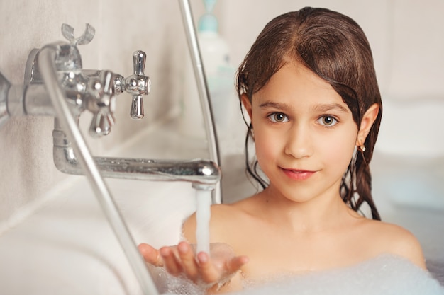 Girl bathing and playing with foam in the bathroom