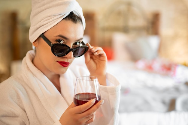 Foto una ragazza in accappatoio con un bicchiere di vino