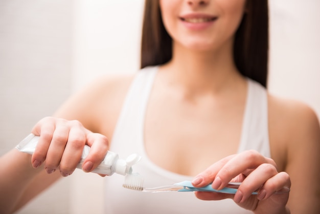 La ragazza in bagno ha messo la pasta sul pennello.