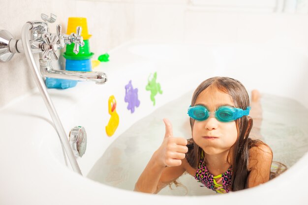 A girl in the bathroom wears swimming glasses