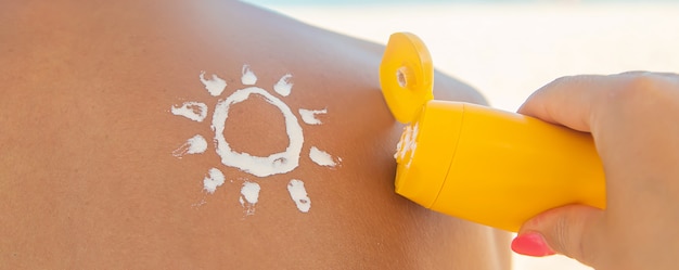 Foto la ragazza sulla spiaggia applica la crema solare sulla pelle di un uomo.