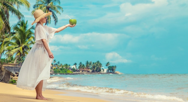 Девушка на пляже пьет кокос