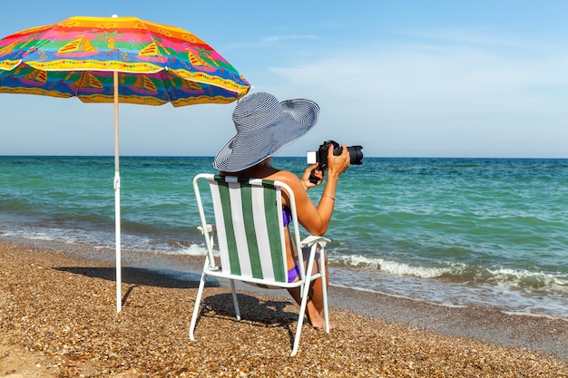 傘の下でラップトップの女性と日光浴の女の子をビーチで女の子