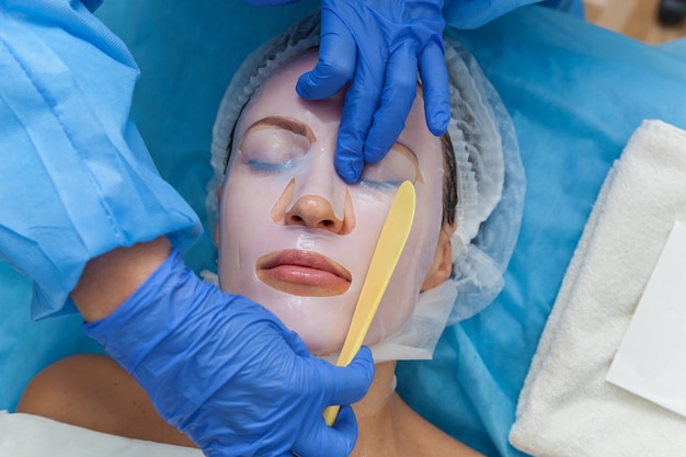 Девушка у косметолога на процедуре омоложения лица с помощью маски