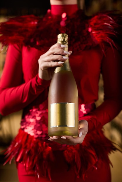 Photo a girl in a beautiful dress holds an expensive bottle of champagne in her hands