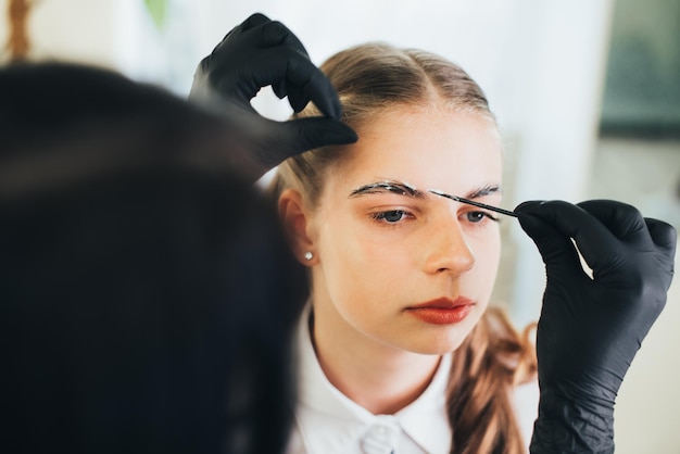 A girl in a beauty salon has an eyebrow lamination procedure, smears with white paste