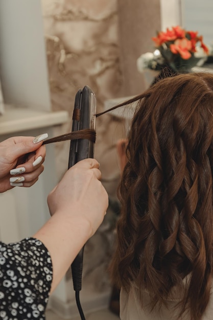 Girl in beauty salon is doing her hair women39s hair styling on flat iron blog aesthetics beauty hair stylists hair curling curling iron space for text