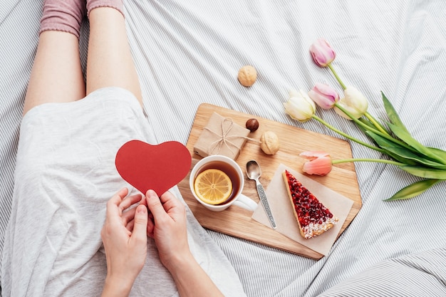 The girl in bed in the morning received flowers, gifts and breakfast in bed. Congratulations on Valentine's Day.