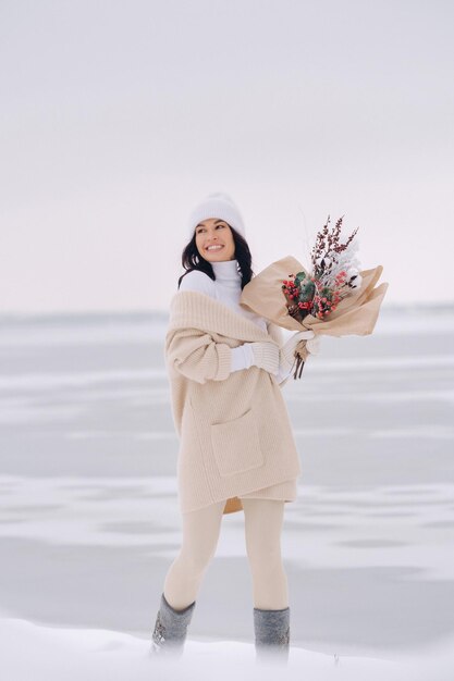 A girl in a beige cardigan and winter flowers walks in nature\
in the snowy season winter weather