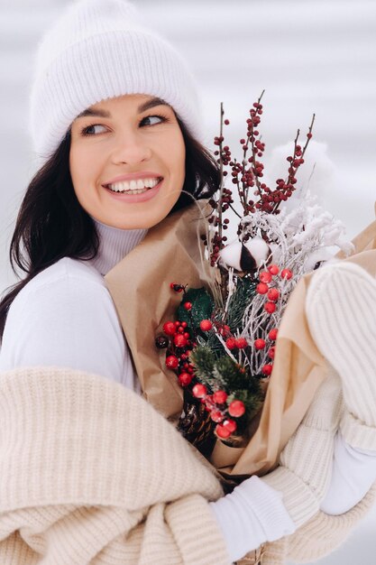 A girl in a beige cardigan and winter flowers walks in nature in the snowy season Winter weather