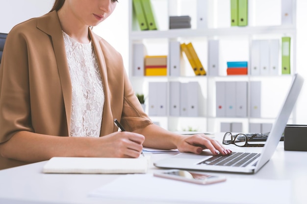 Girl in beige cardigan writing and typing