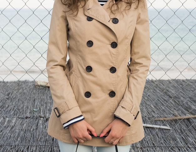 Girl in a beige coat on the coast