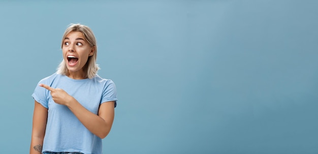 Girl being charmed and excited visiting awesome event pointing and staring left amazed and delighted