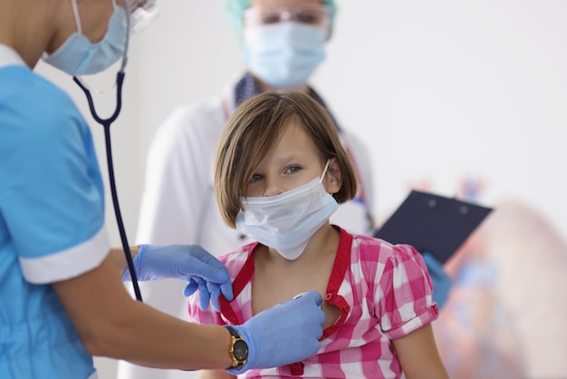 Ragazza esaminata dal medico pediatra con lo strumento dello stetoscopio