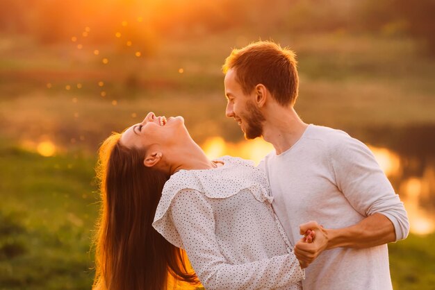 The girl bend her back while dancing with her boyfriend on the evening nature