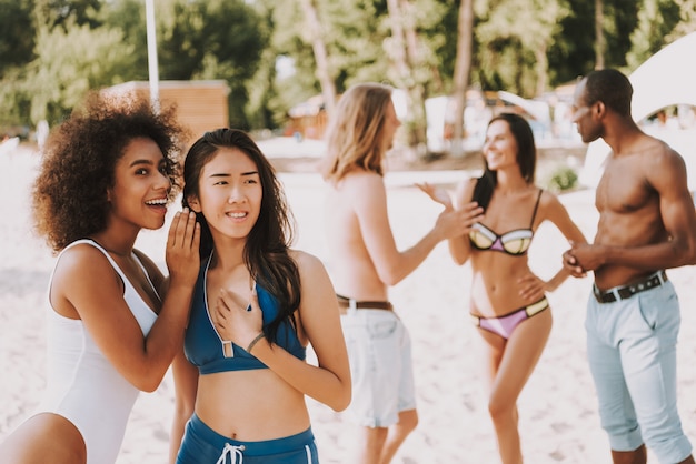 Ragazza in bikini flirt sulla spiaggia le donne spettegolare