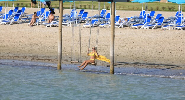 girl in a bikini swinging on a swing on the shore