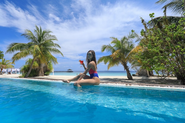 девушка в бикини в тропическом бассейне, глядя на океан