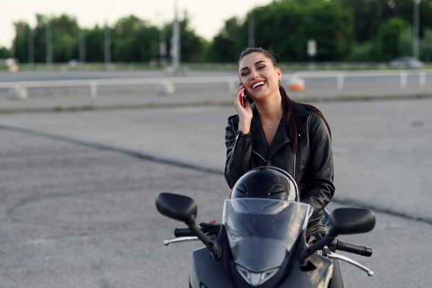 Girl in black clothes on outdoors parking with motorcycle