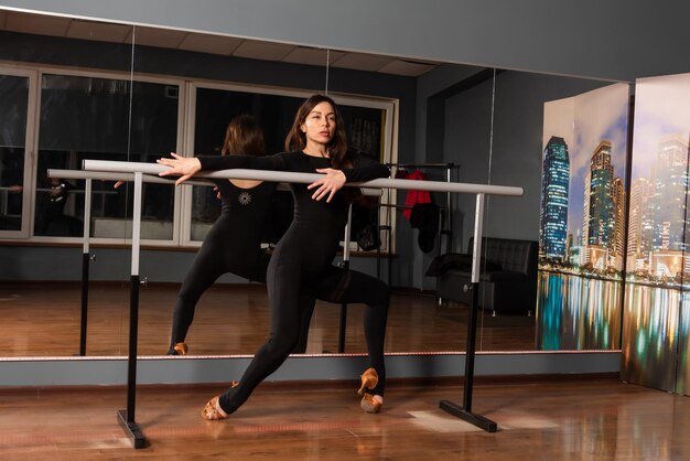 Girl in black dress are training in dance studio