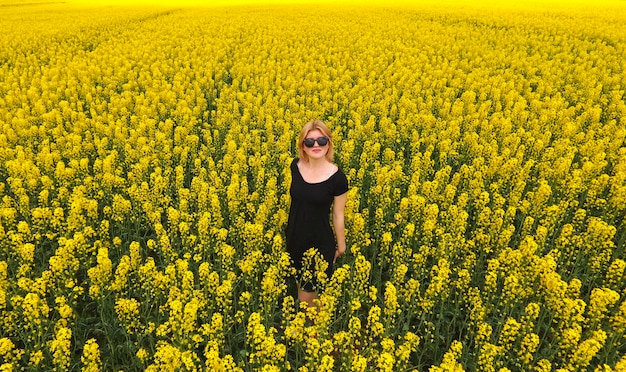 A girl in a black dress among the colors of rape in the field W