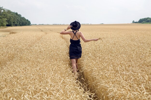 Girl in a black dress and a hat running