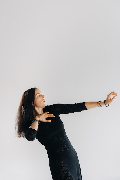 A girl in a black dress moves in a dance on a gray background Dynamic dance