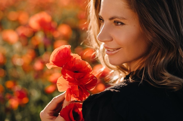 Foto una ragazza in un vestito nero su un campo di papaveri al tramonto