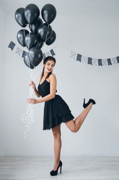 Girl in a black dress with black balloons