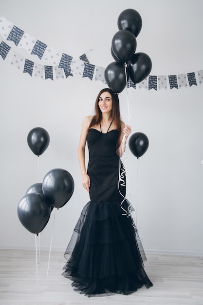 Girl in a black dress with black balloons