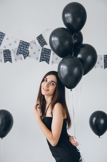 Girl in a black dress with black balloons