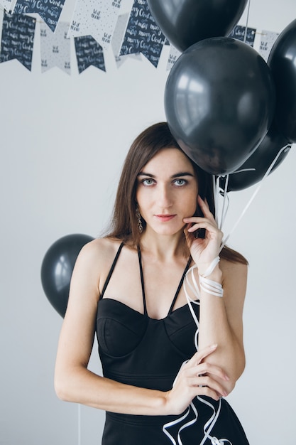 Girl in a black dress with black balloons