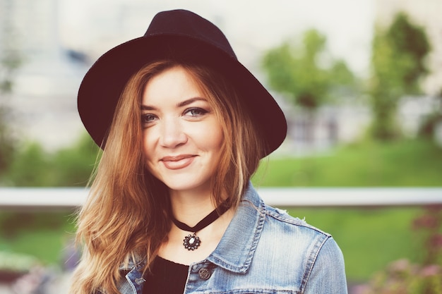 A girl in a black hat is walking in the city.