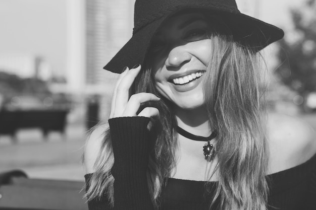 A girl in a black hat is walking in the city.