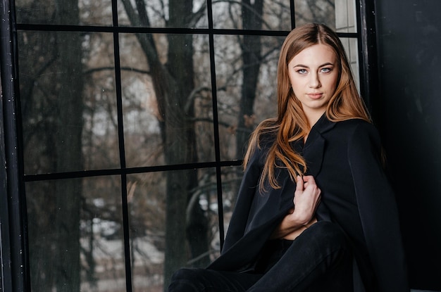 girl in a black jacket sitting on the windowsill