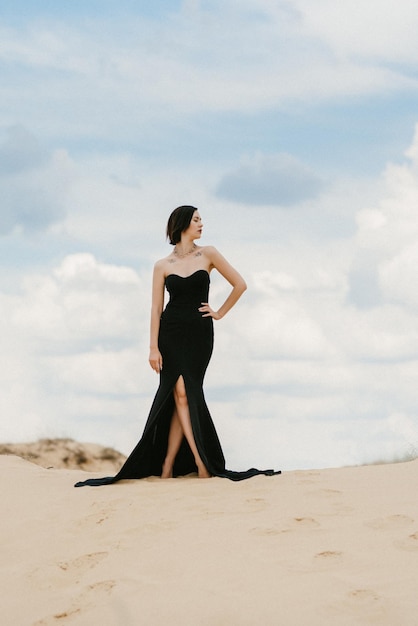 Girl in a black long dress in a sandy desert