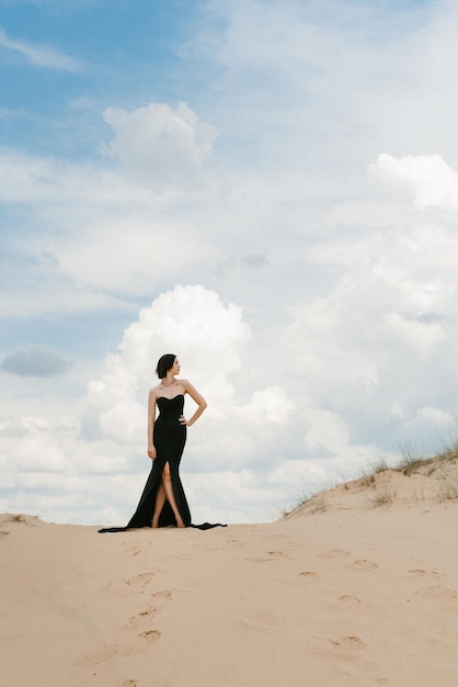 Ragazza in un abito lungo nero in un deserto sabbioso