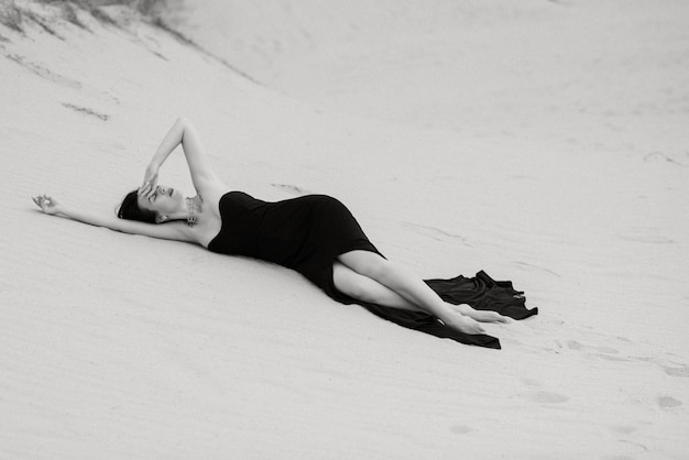 砂の砂漠で黒い長いドレスを着た女の子