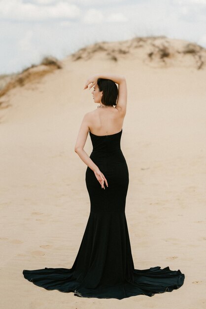 모래 사막에서 검은 긴 드레스를 입은 소녀