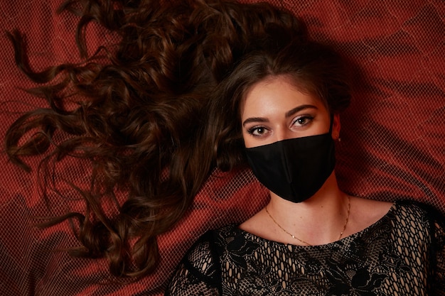 A girl in a black mask is lying on the bed