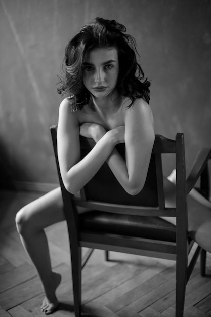 Girl in black panties with black curly hair posing in a vintage interior black and white photo