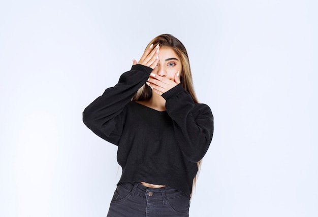 Girl in black shirt looking through fingers.