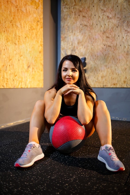 Girl in a black suit in the gym with a sports ball