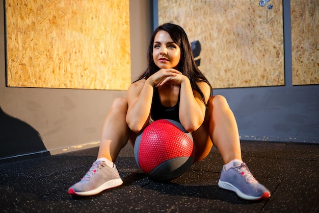 Girl in a black suit in the gym with a sports ball