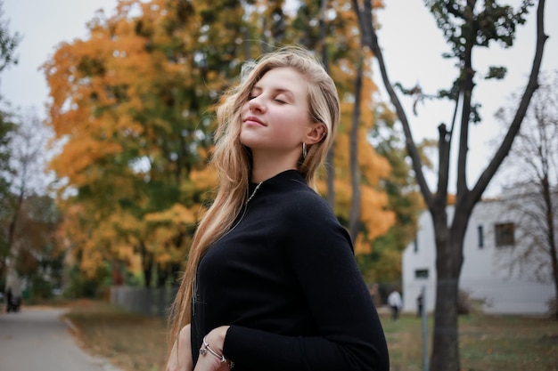 Girl in a black sweater and chain closes her eyes