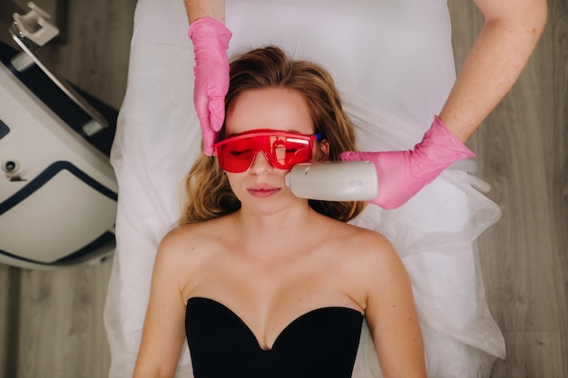 A girl in black underwear gets laser hair removal on her body in the salon