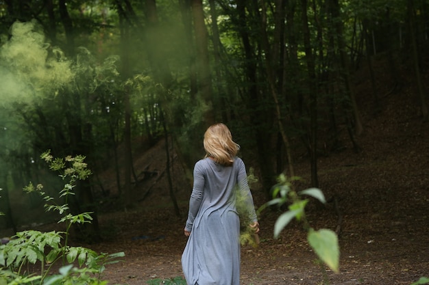 Girl blonde walks through the forest alone 