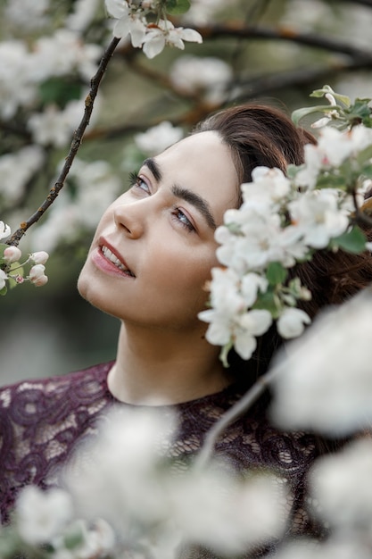 Girl in a blooming garden in a maroon dress