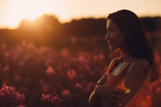 Девушка на цветущем цветочном поле Салли на закате. Сиреневые цветы и женщина.